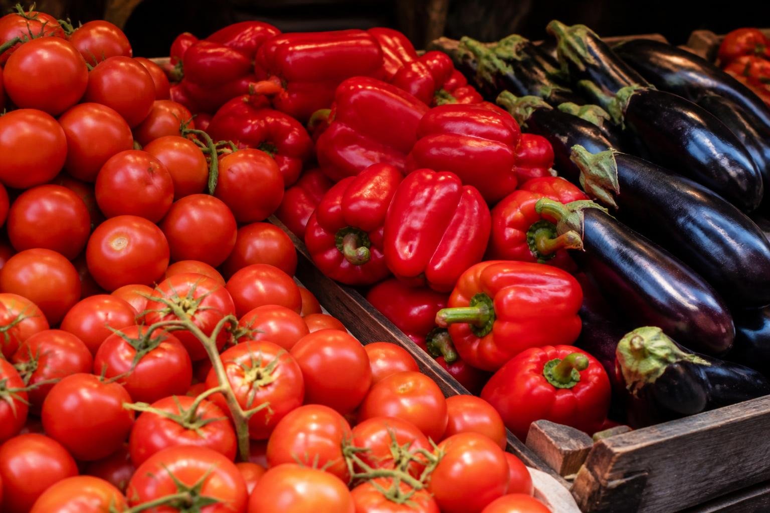Tomates mûres, poivrons rouges et aubergines brillantes sur un étal d'été